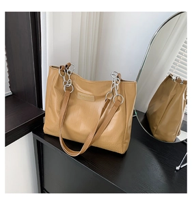 Close-up of light brown crocodile pattern tote bag with silver chain strap and logo