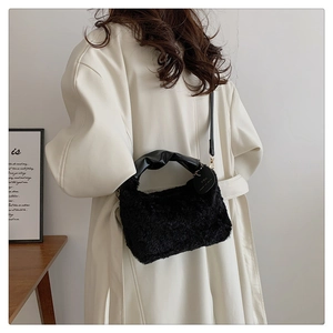 Detail of black plush handbag featuring twisted leather handle and heart charm pendant