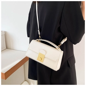Detailed view of elegant white handbag with golden round metal lock and textured leather