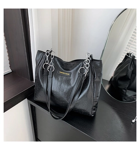 Detail of black crocodile pattern tote bag featuring silver chain and fashion tag
