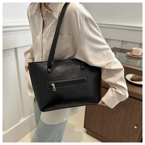 Detail of minimalist black PU leather tote bag with functional front zipper and thin straps