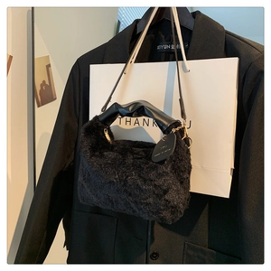 Detail of black plush hobo bag featuring knotted leather handle and gold chain accents