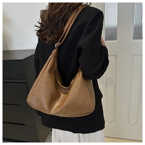 Detail of retro brown crescent tote bag showing smooth leather texture and metal buckles