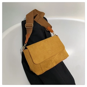 Detail of mustard yellow matte shoulder bag with suede texture and wide brown strap