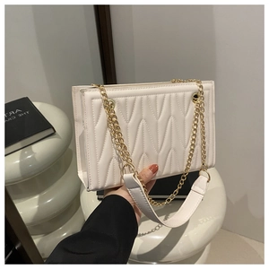 Detail of white PU leather tote with V-quilted texture and gold chain shoulder strap