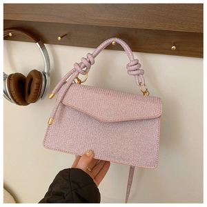 Close-up of pink sequined envelope bag featuring a knotted handle and metallic hardware