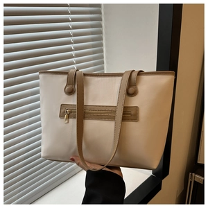 Close-up of beige tote bag featuring a front zipper pocket and khaki shoulder straps