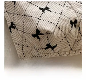 Detail of corduroy bag featuring black diamond quilting and cute bow print patterns