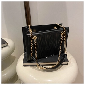 Detail of black quilted faux leather tote with M-shaped stitching and gold chain straps