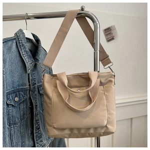 Detailed macro view of beige canvas tote bag with metal snap pocket and sturdy woven strap