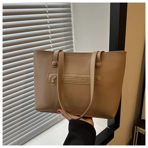 Detail view of khaki faux leather tote bag showing smooth texture and horizontal zipper pocket