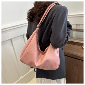 Lifestyle view of a large pink soft leather hobo bag worn with a casual blazer