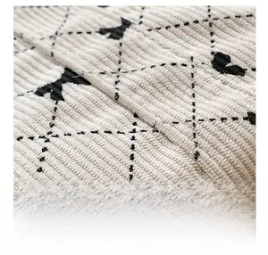 Macro detail of beige corduroy fabric with black quilted diamond pattern and mini bows