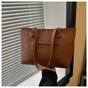 Detail of a brown matte faux leather tote bag showing the exterior zipper pocket and stitching