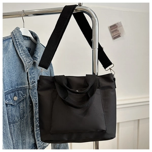 Detail of waterproof black nylon tote bag with wide woven strap on hanger