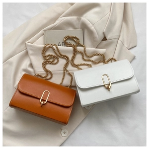 Detail of minimalist chain shoulder bags in brown and white with golden metal ring clasps
