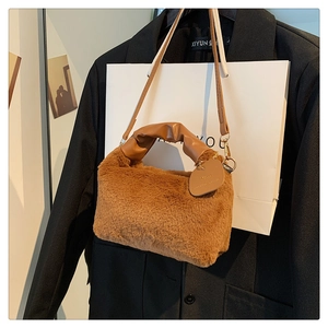 Detailed texture of brown plush hobo bag with pleated leather handle and detachable strap