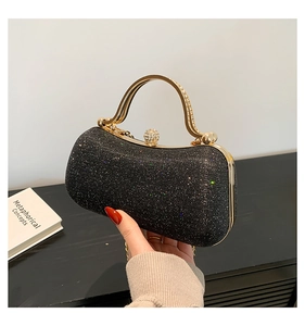 Détail du sac de soirée pailleté noir avec poignée dorée sertie de cristaux et fermoir