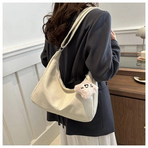 Close-up of cream faux leather hobo bag with pebble texture and pink star charm