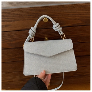 Detail of silver textured handbag with metallic finish and gold ring rope handle