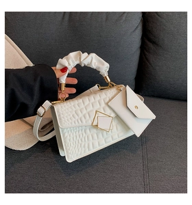 Detail of white crocodile embossed handbag with cloud pleated handle and gold clasp