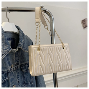 Macro detail of vertical V-shape quilted pattern on white faux leather shoulder bag