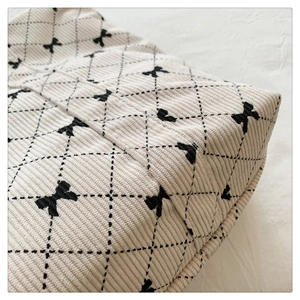 Detailed texture of corduroy fabric with black bow embroidery and diamond quilting