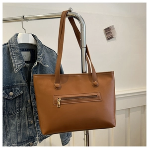 Detail of vintage brown tote bag featuring outer zipper pocket and golden hardware accents