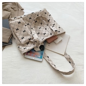 Detail of beige corduroy tote set with black argyle and bow pattern on soft fabric
