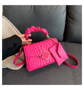 Detail of fuchsia crocodile pattern handbag with pleated handle and gold geometric lock