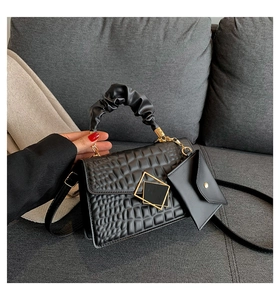 Detail of black crocodile embossed handbag with cloud handle and gold square clasp