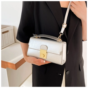 Silver metallic leather shoulder bag with gold square clasp worn on a black blazer