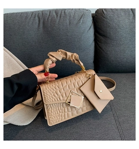 Detail of beige crocodile pattern handbag with cloud-shaped handle and gold clasp