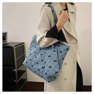 Detail of light blue corduroy tote bag with black bow print and matching mini pouch