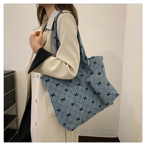 Detail view of light blue corduroy tote bag with quilted diamond pattern and black bows
