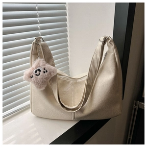 Detail of off-white lychee textured leather bag with silver zipper and pink plush charm