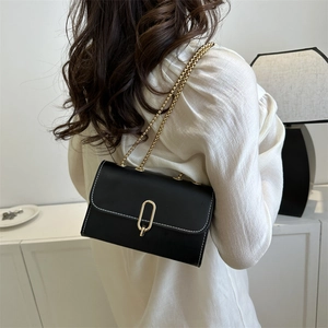 Minimalist black faux leather crossbody bag with white stitching and gold chain strap
