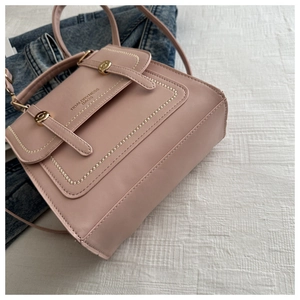 Detailaufnahme der rosa PU-Leder-Aktentasche mit Goldschnallen auf Denim-Hintergrund
