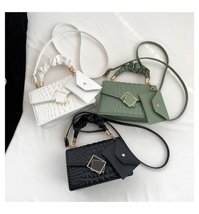 Detailed view of crocodile pattern handbags in white, green and black with metal buckles