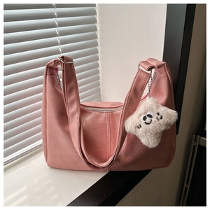 Detail of pink PU leather crescent bag with decorative stitching and plush charm