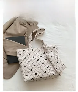 Detail of corduroy tote bag with black bow diamond pattern against minimalist background