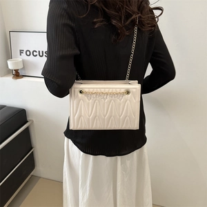 Chic cream white quilted tote bag with gold chain strap shown on a model's shoulder