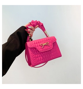 Detail of rose red croc-effect bag featuring gold bow hardware and cloud pleated handle