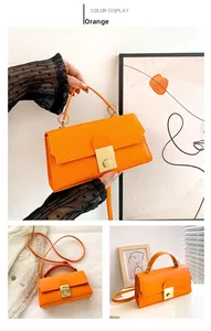 Detailed view of an orange faux leather handbag with a round gold metal lock and top handle