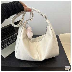 Detail of cream hobo shoulder bag with textured leather and pink plush pendant charm