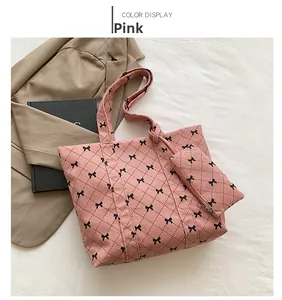 Detailed view of pink corduroy tote with bow patterns and matching small zipper pouch