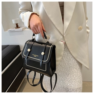 Detail of a black matte PU leather mini backpack with white stitching and gold locks