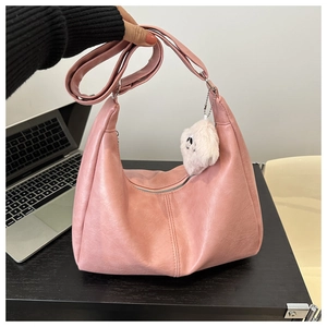 Close-up of pink PU leather crescent shoulder bag with cute plush bear charm detail