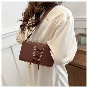 Gros plan d'un sac en cuir verni marron avec détails de lacets et œillets sur un modèle