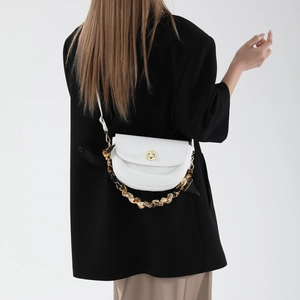 White semi-circular crossbody saddle bag with gold lock and amber chain strap on model